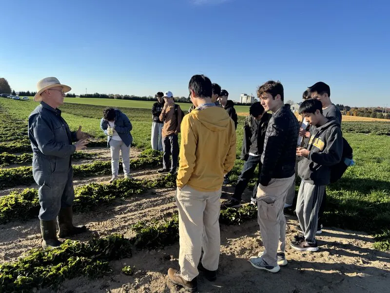 SPAIS members listening to their farm host beside a growing bed.